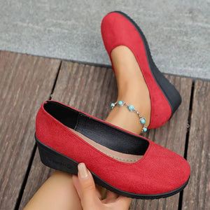 Red textured round toe wedge slip-ons with a low wedge heel and slip-on style.