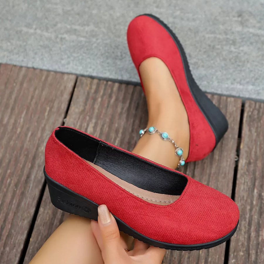 Red textured round toe wedge slip-ons with a low wedge heel and slip-on style.