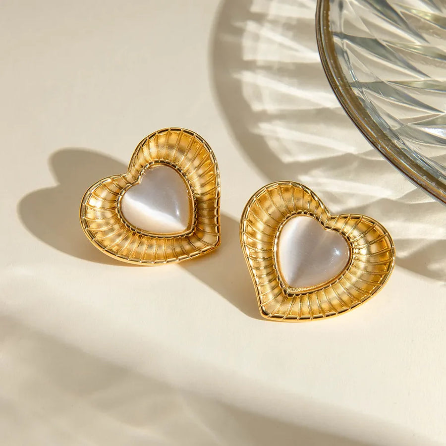 Golden heart cabochon stud earrings with ribbed gold frames and iridescent white centers.