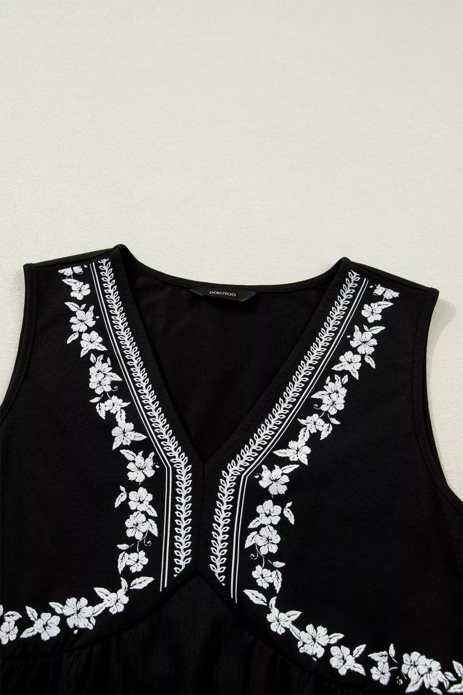 Black sleeveless v-neck top with white floral embroidery
