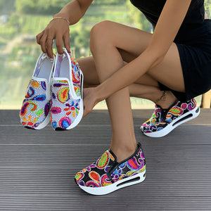 Vibrant slip-on platform sneakers with colorful paisley print and white soles.
