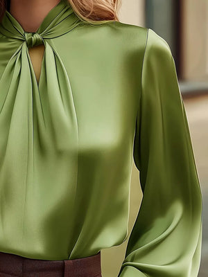 Green satin blouse with tie-neck detail and cutout, long sleeves.