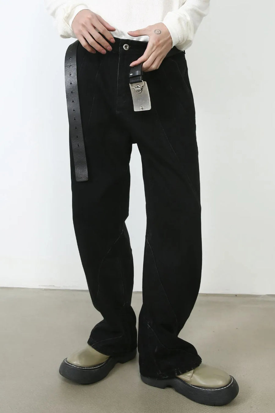 Dark denim trousers with sculpted seams and a black leather belt.