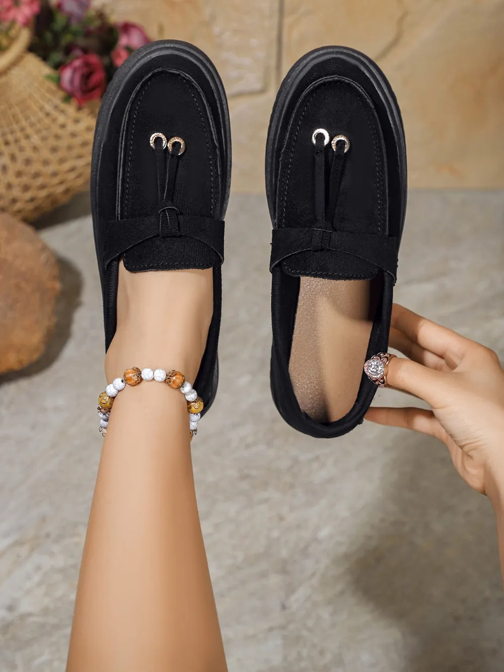 Black suede loafer slides with tassel detail and gold hardware.