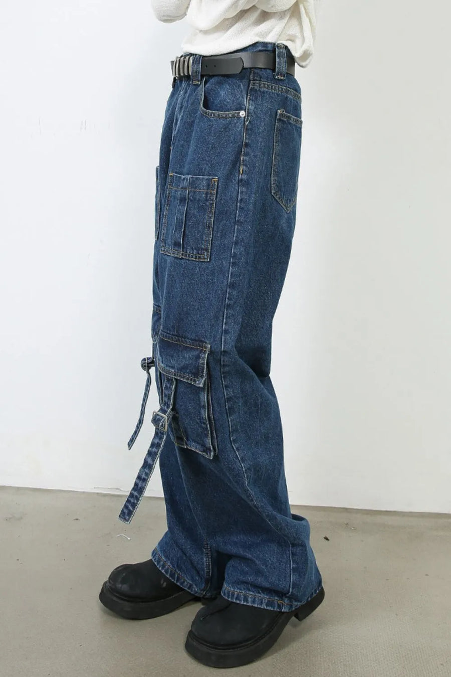 Utility denim cargo pants in medium wash with buckle strap pocket details and wide leg.