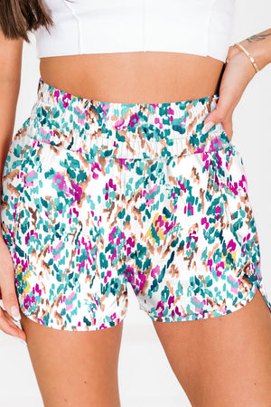 White running shorts with a colorful abstract brushstroke print and elastic waistband.