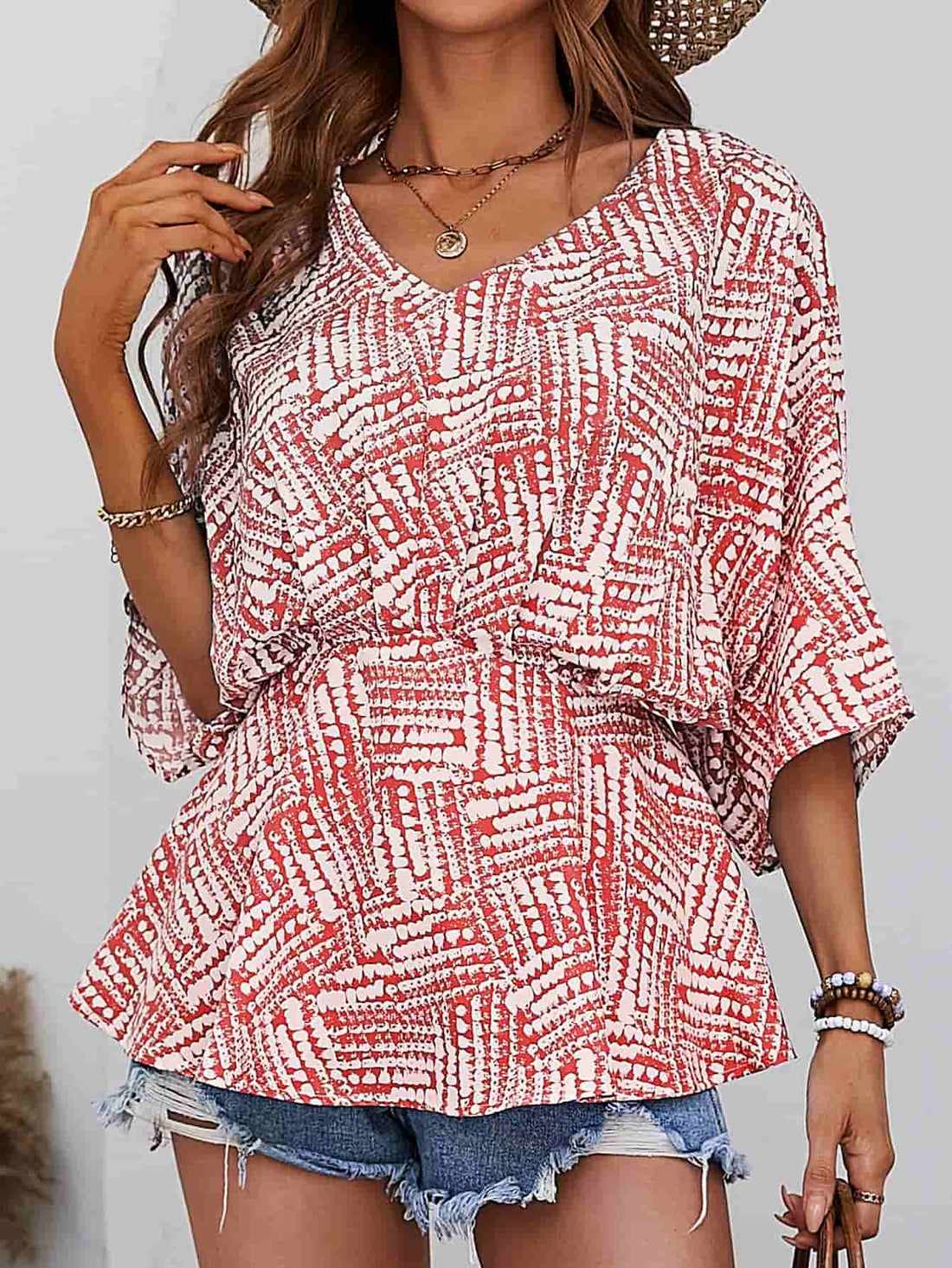 Abstract print cinched waist blouse with V-neck and short sleeves in scarlet.