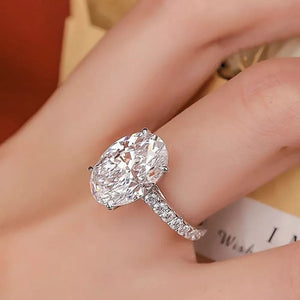 Elegant moissanite oval ring in sterling silver with a pavé band.