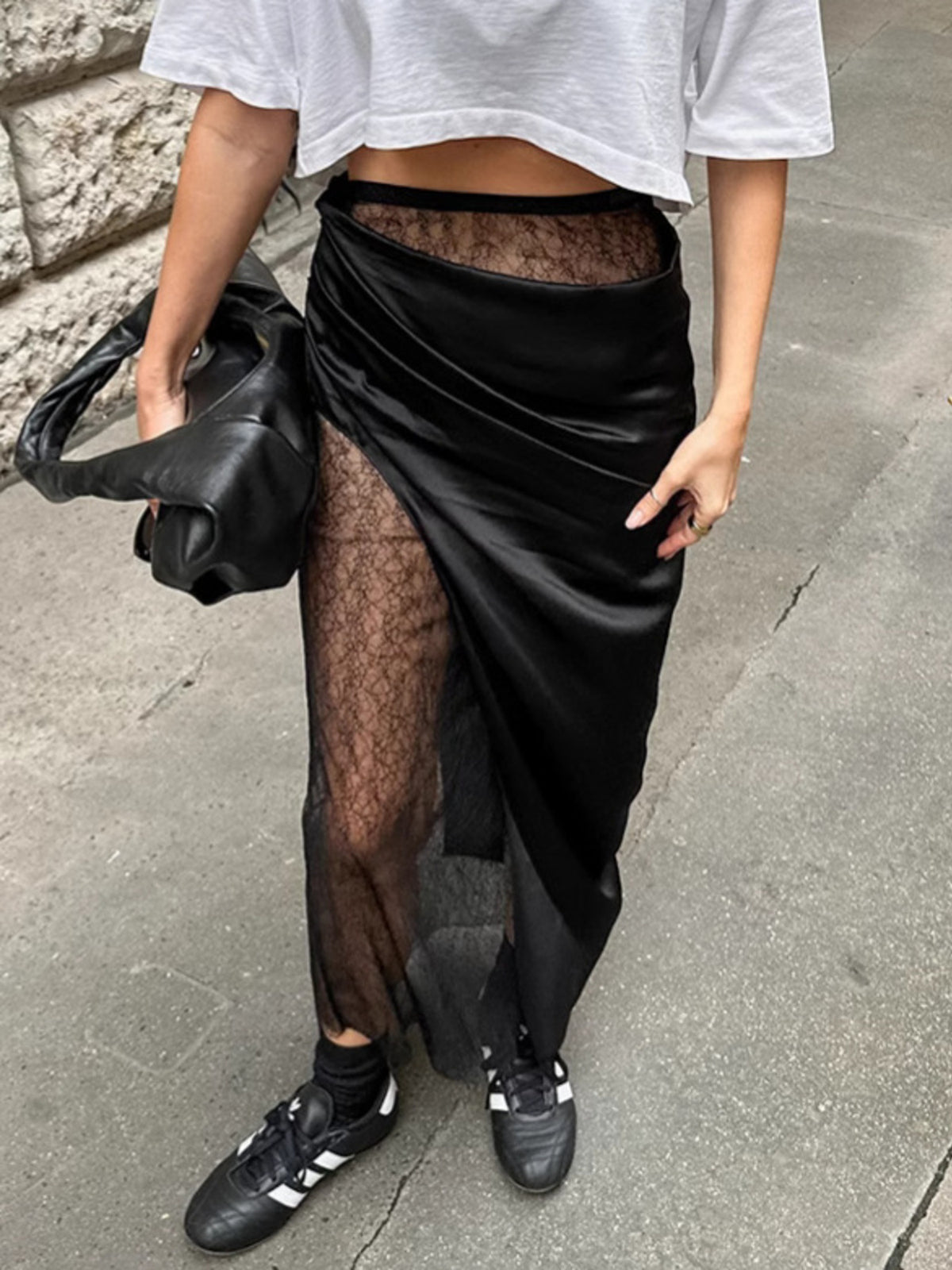 Black midi skirt with sheer lace panels and asymmetrical wrap detail.