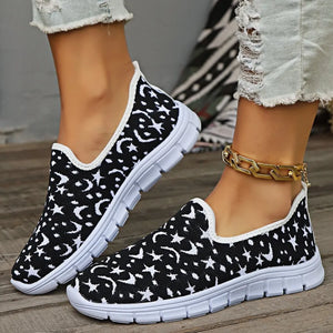 Black knit slip-on sneakers with white celestial pattern and white soles.