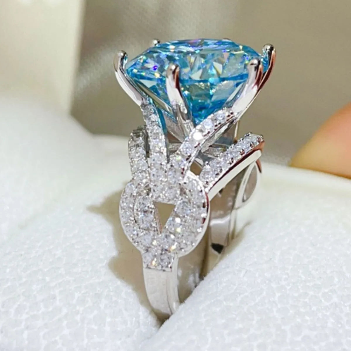 Celestial blue moissanite knot ring with pave diamond accents.