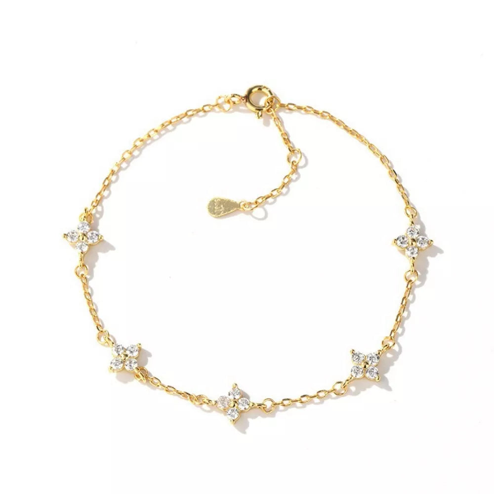 Gold chain bracelet with five sparkling clover charms.