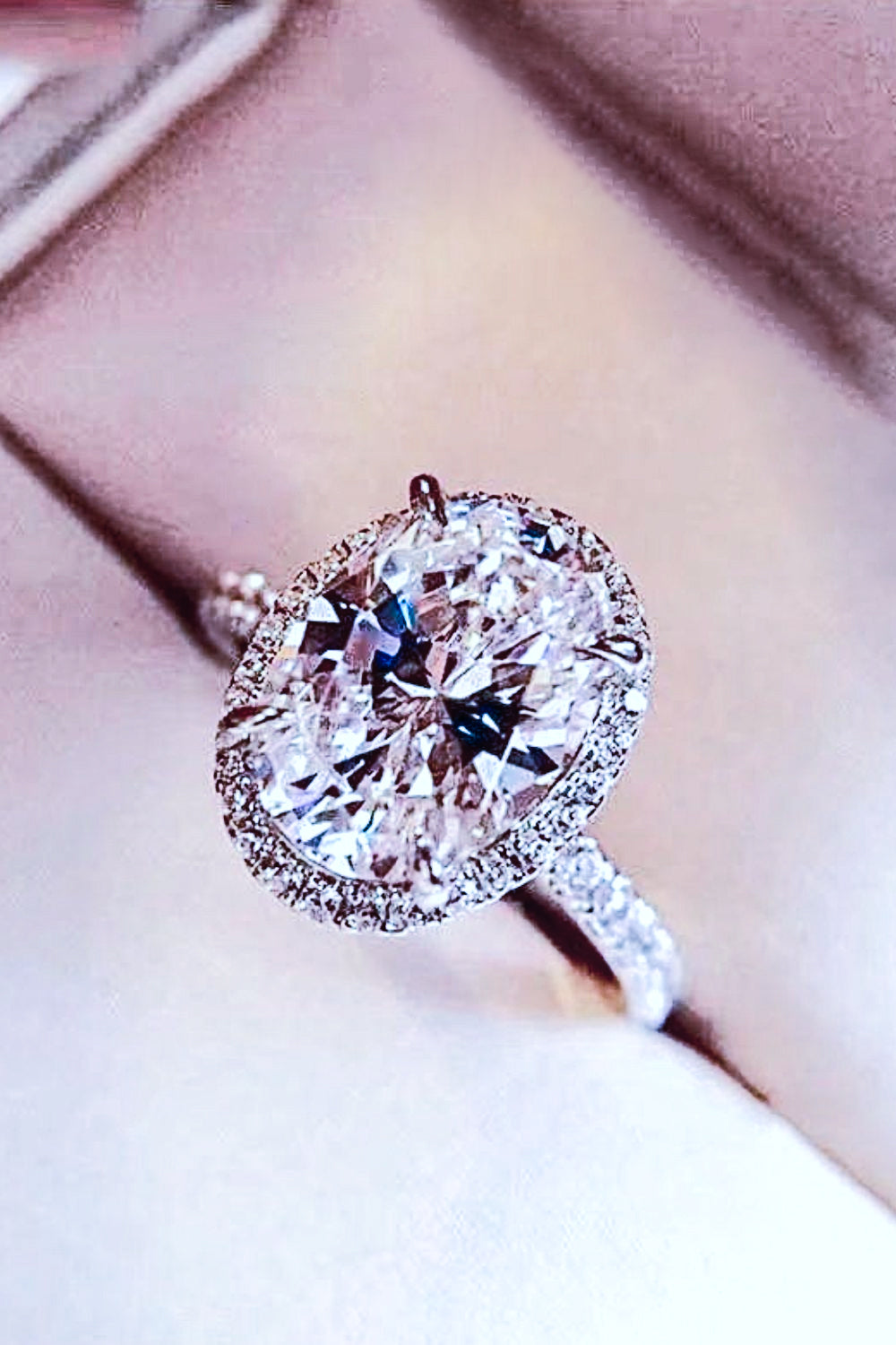 Halo oval diamond engagement ring in white gold with pave band.