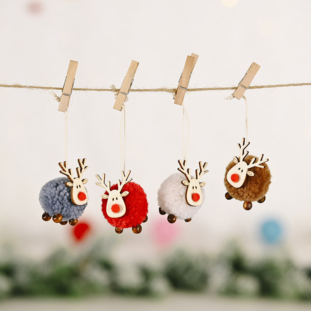 Four multicolor pom-pom reindeer ornaments with wooden antlers and red noses hang on a string.