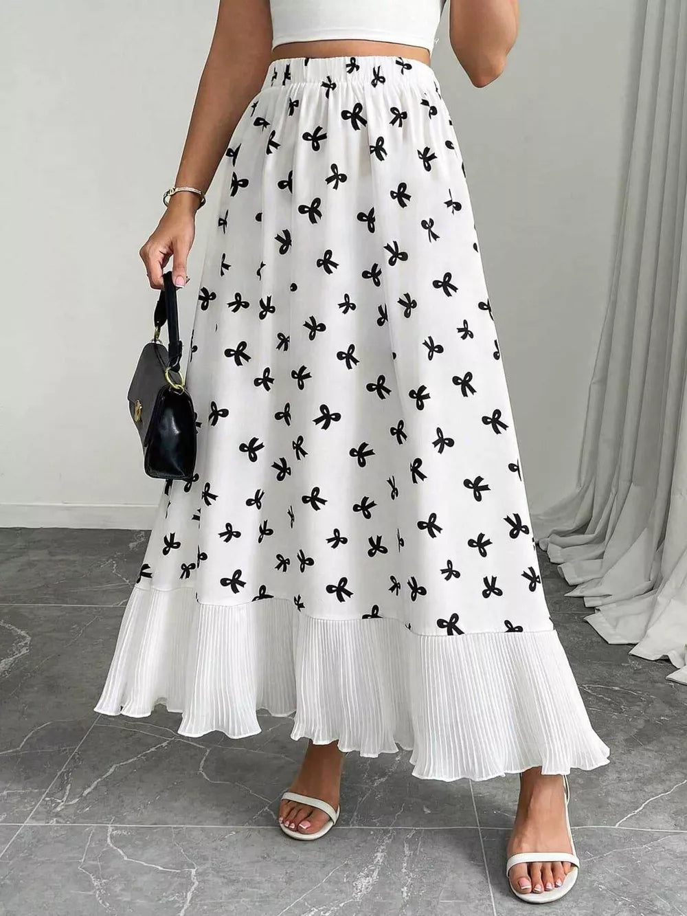 White maxi skirt with black bow print and ruffled hem.