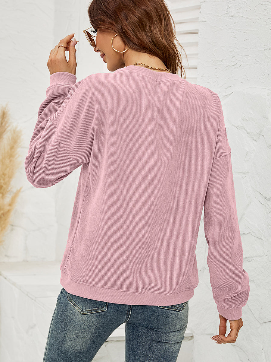 Dusty Pink corduroy sweatshirt with crewneck and long sleeves, styled with jeans.