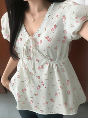 White floral blouse with puff sleeves, V-neck, lace trim, and tie detail.