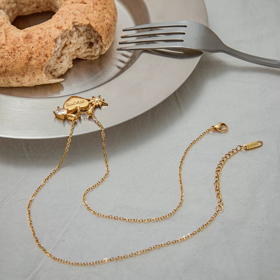 Gold heart charm necklace with cubic zirconia and starburst detail, dainty chain.