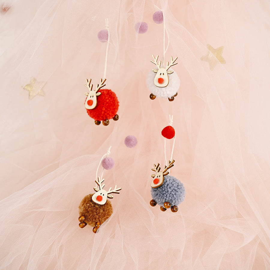 Four multicolor pom-pom reindeer ornaments with wooden antlers and red noses hang on strings.