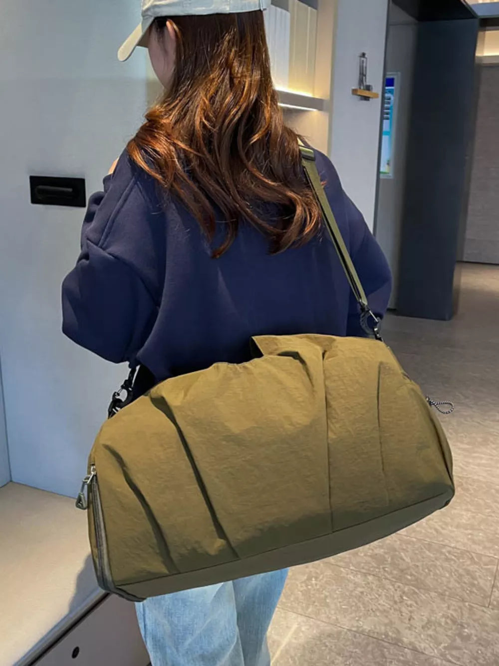 Olive green nylon duffel bag with ruched detailing and silver zipper.