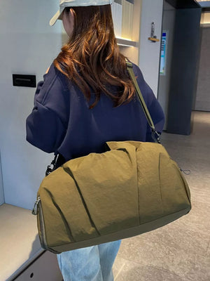 Olive green nylon duffel bag with ruched detailing and silver zipper.