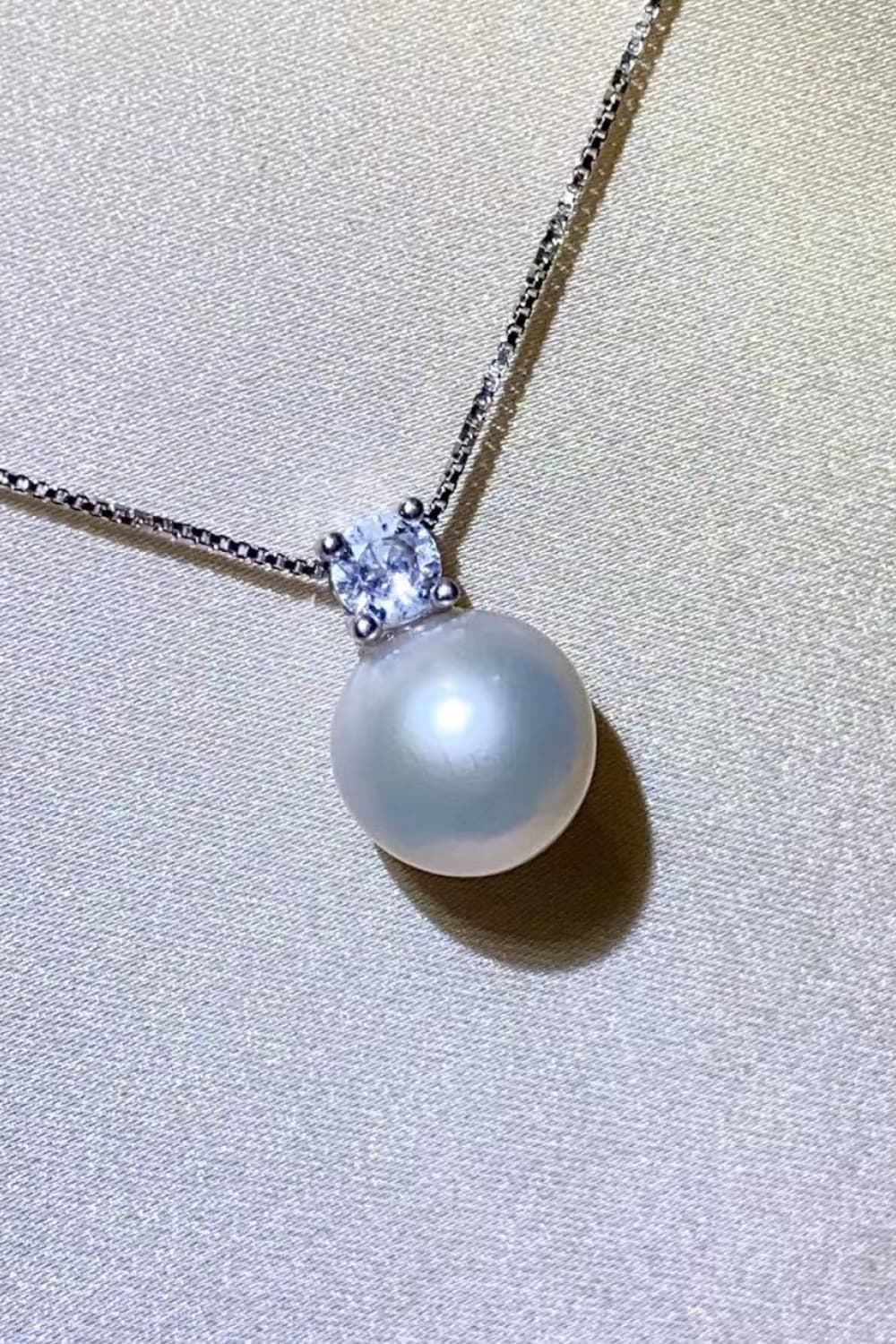 Solitaire pearl pendant necklace in silver with a cubic zirconia accent on a delicate chain.