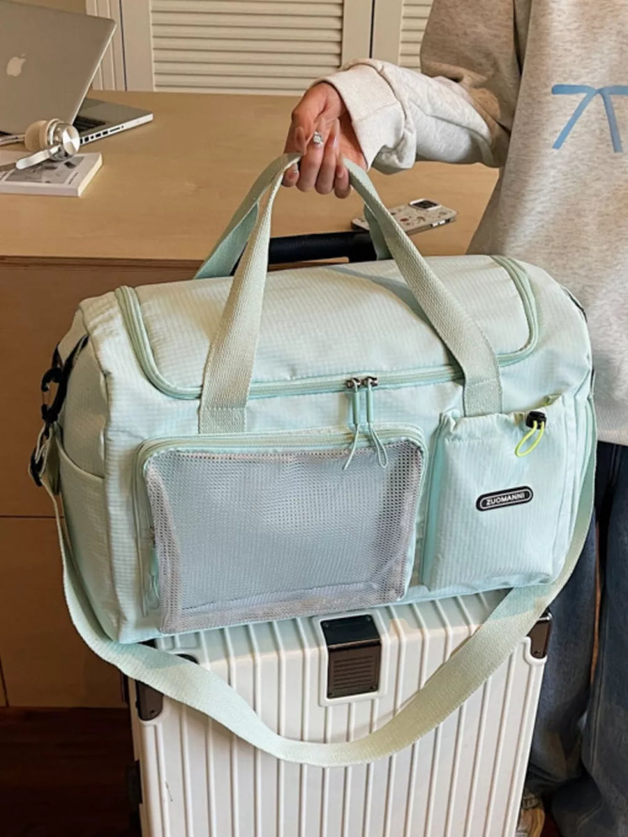 Light blue duffel bag with mesh pocket and dual handles, styled with a grey hoodie.