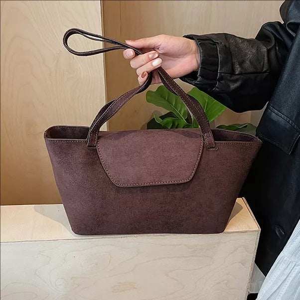 Brown suede flap tote bag with top handles and a detachable wrist strap.
