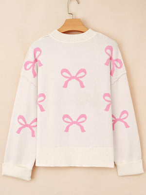 Beige drop shoulder sweater with allover pink bow print, acrylic blend.