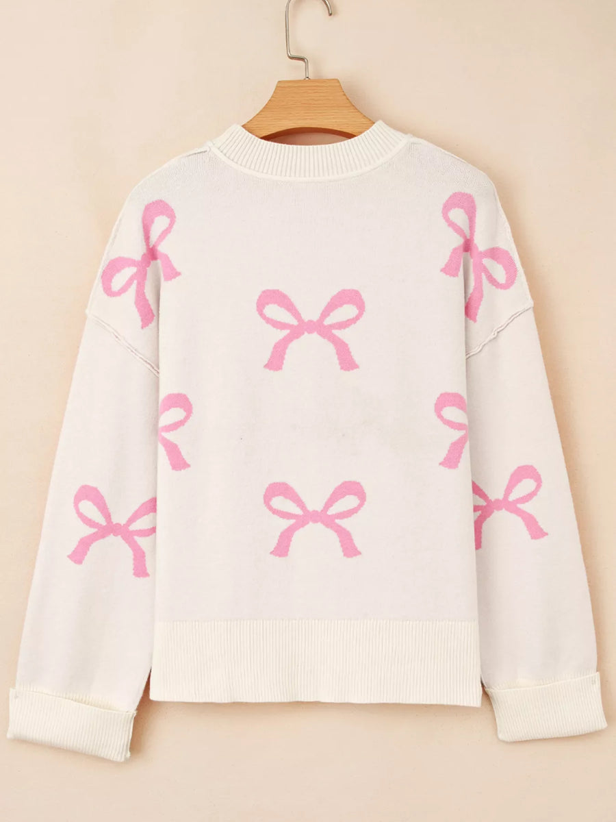 Beige drop shoulder sweater with allover pink bow print, acrylic blend.