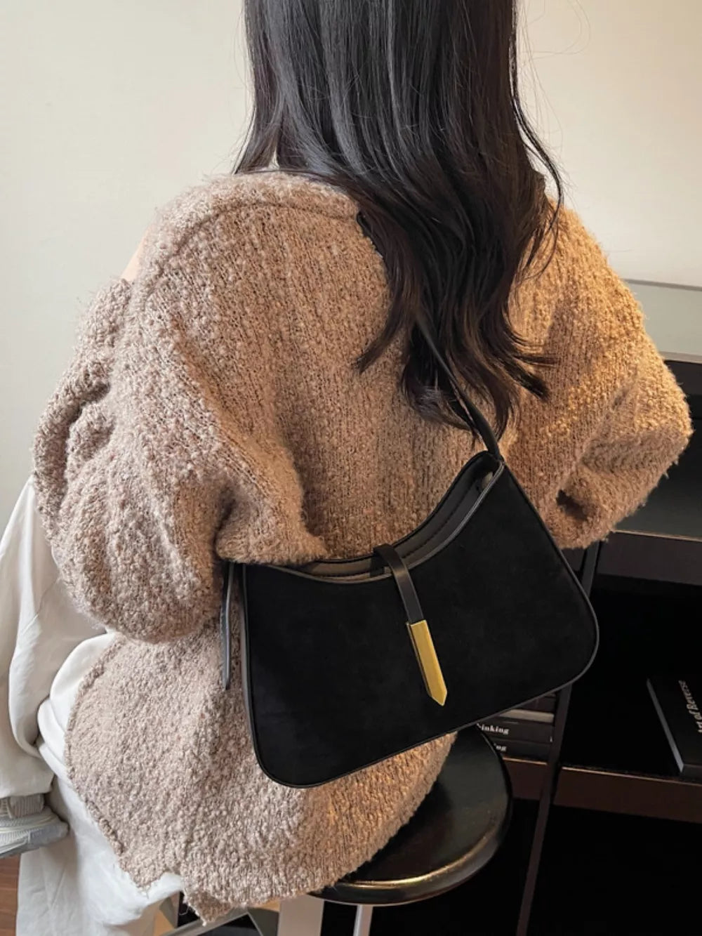 Black suede and leather shoulder bag with gold accent detail.