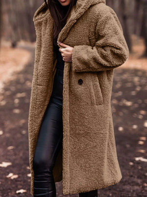 Brown teddy bear longline coat with hood and button closure, worn open over black pants.