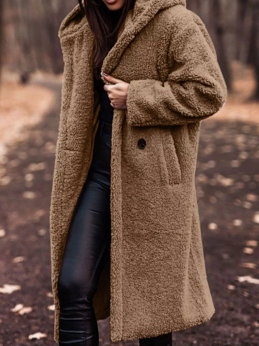 Brown teddy bear longline coat with hood and button closure, worn open over black pants.