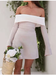Eggshell off-shoulder dress with flare sleeves and a-line skirt, styled with a straw bag and flowers.