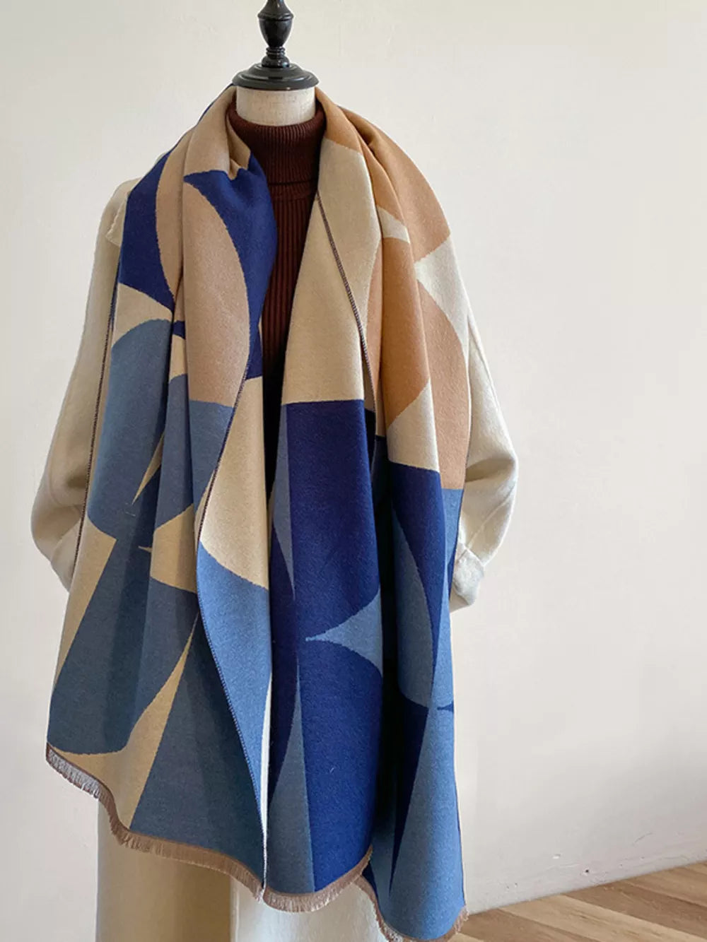 Geometric patterned soft scarf in light indigo and beige with fringe details.