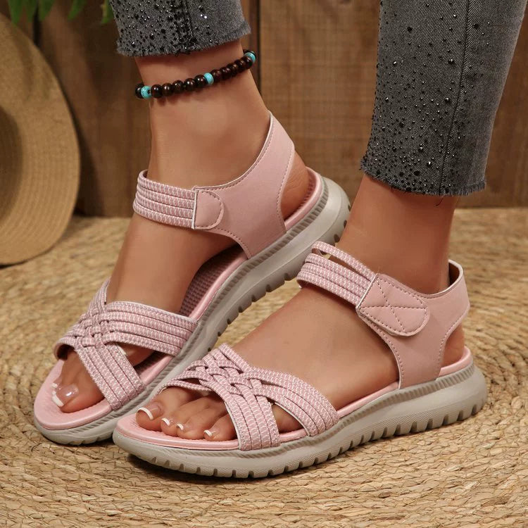 Pink woven strap open-toe flat sandals with adjustable hook-and-loop closure.