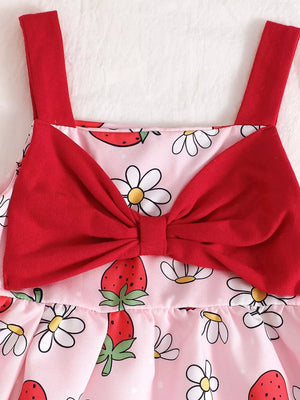 Baby dress in pink with strawberry and daisy print, featuring red straps and a large red bow.