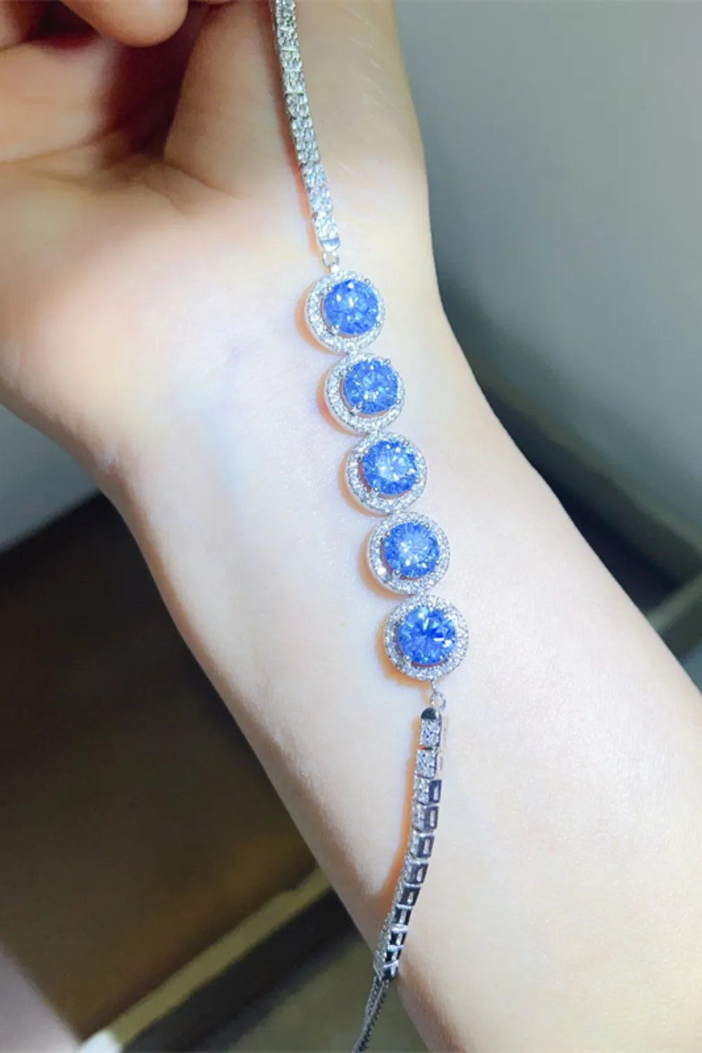 Blue moissanite and diamond tennis bracelet in silver with halo settings.