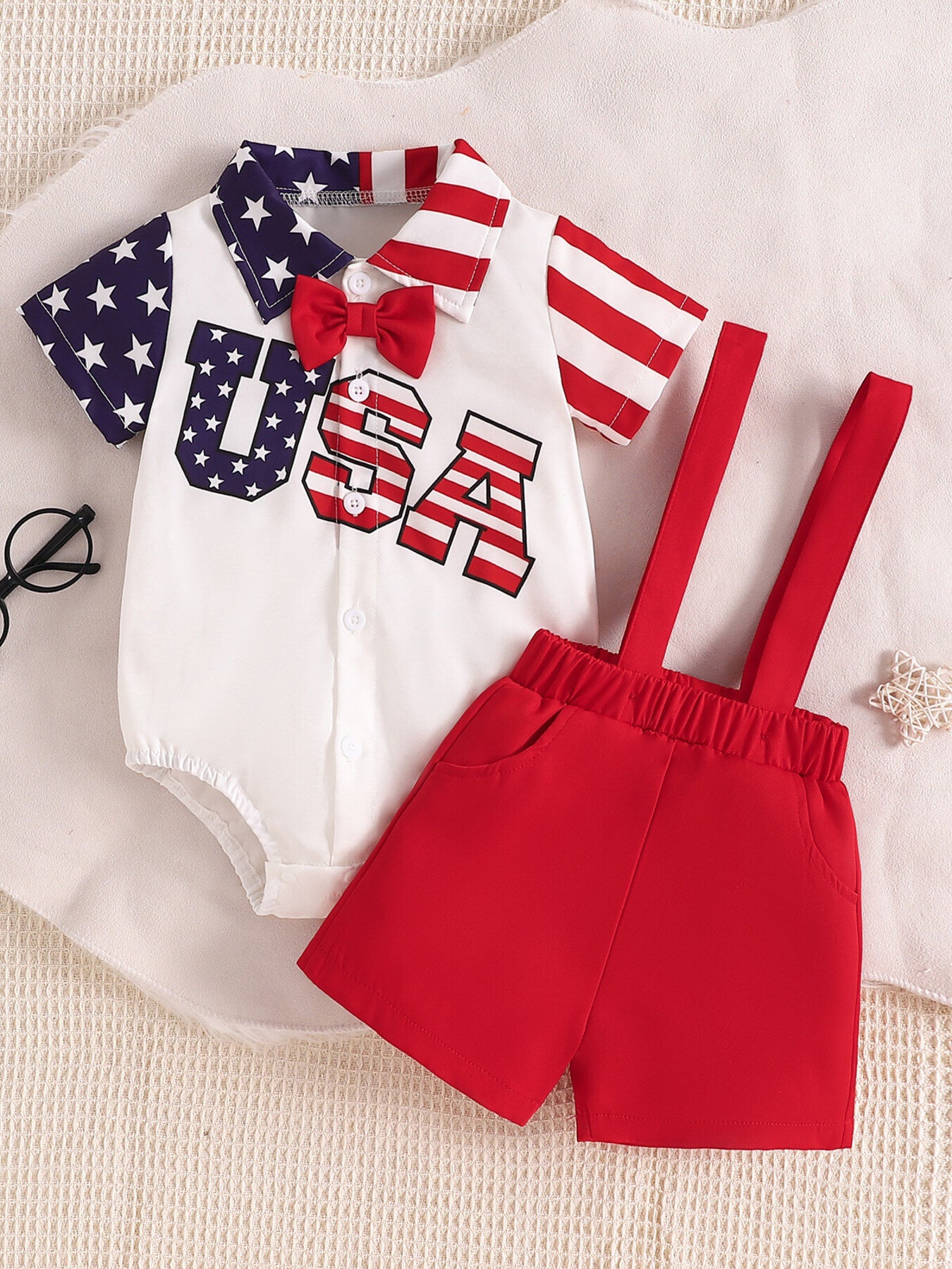 Patriotic baby bodysuit and overalls set with USA graphic, red bow tie, star sleeves, striped collar and sleeves.