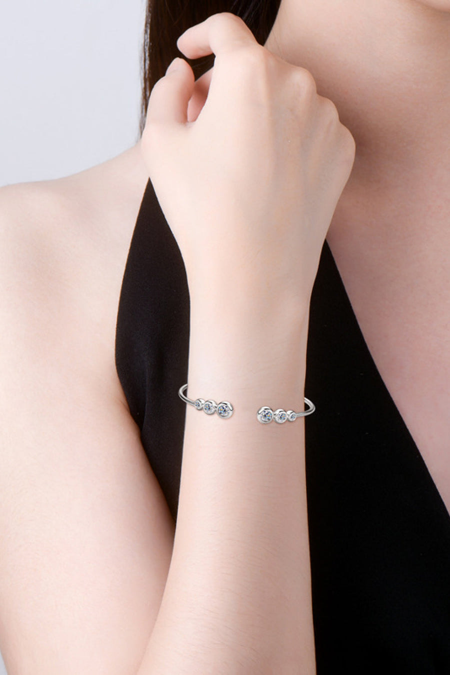 Silver open-ended cuff bracelet with five round moissanite stones.