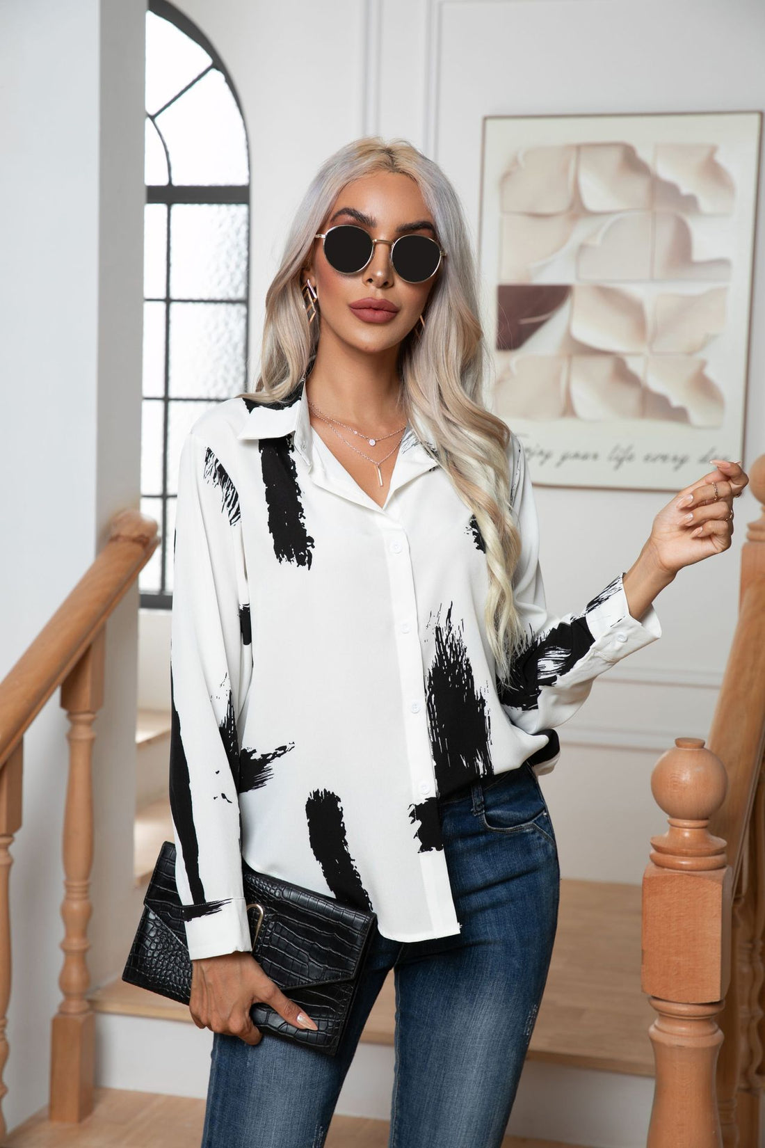 White abstract brushstroke blouse with button front and collar, styled with jeans and clutch.
