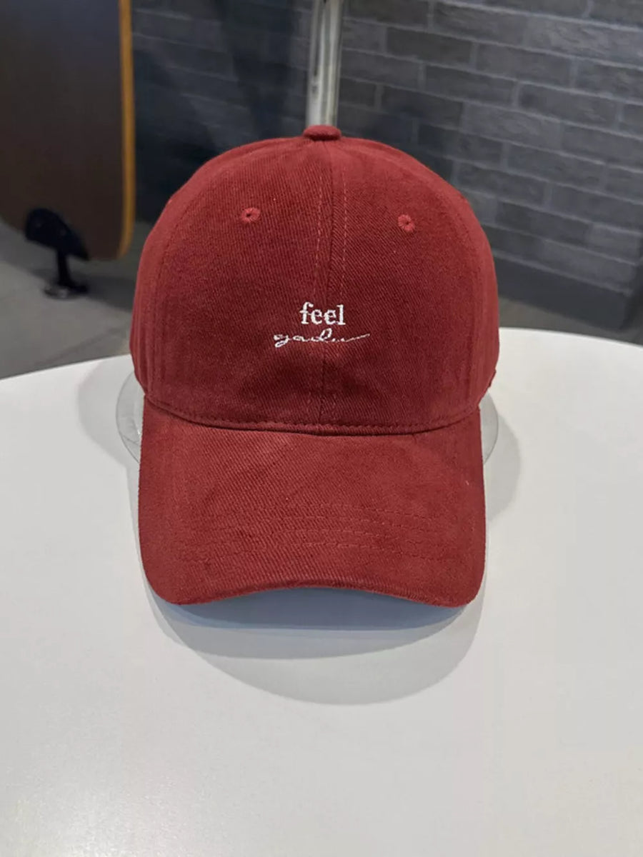 Red baseball cap with embroidered "feel good" text detail.
