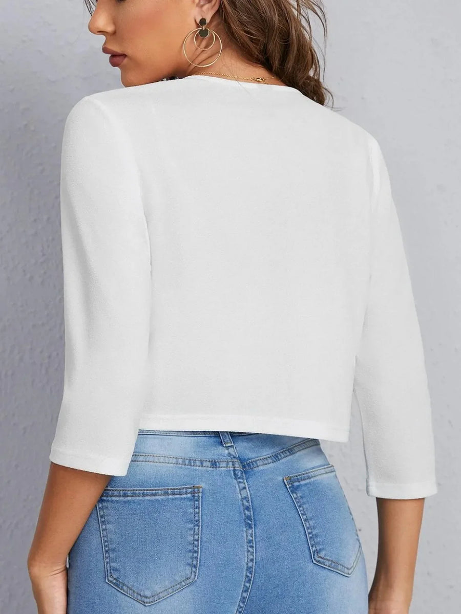 White cropped open-front blazer with elbow sleeves and a textured finish.