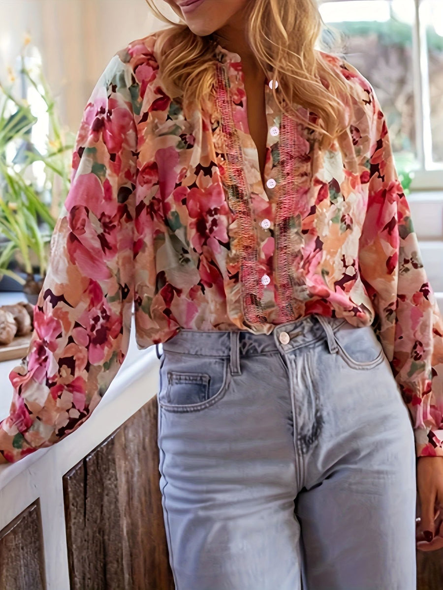 Frill trim button-up shirt with a vibrant floral print and long sleeves, styled with light wash denim jeans.