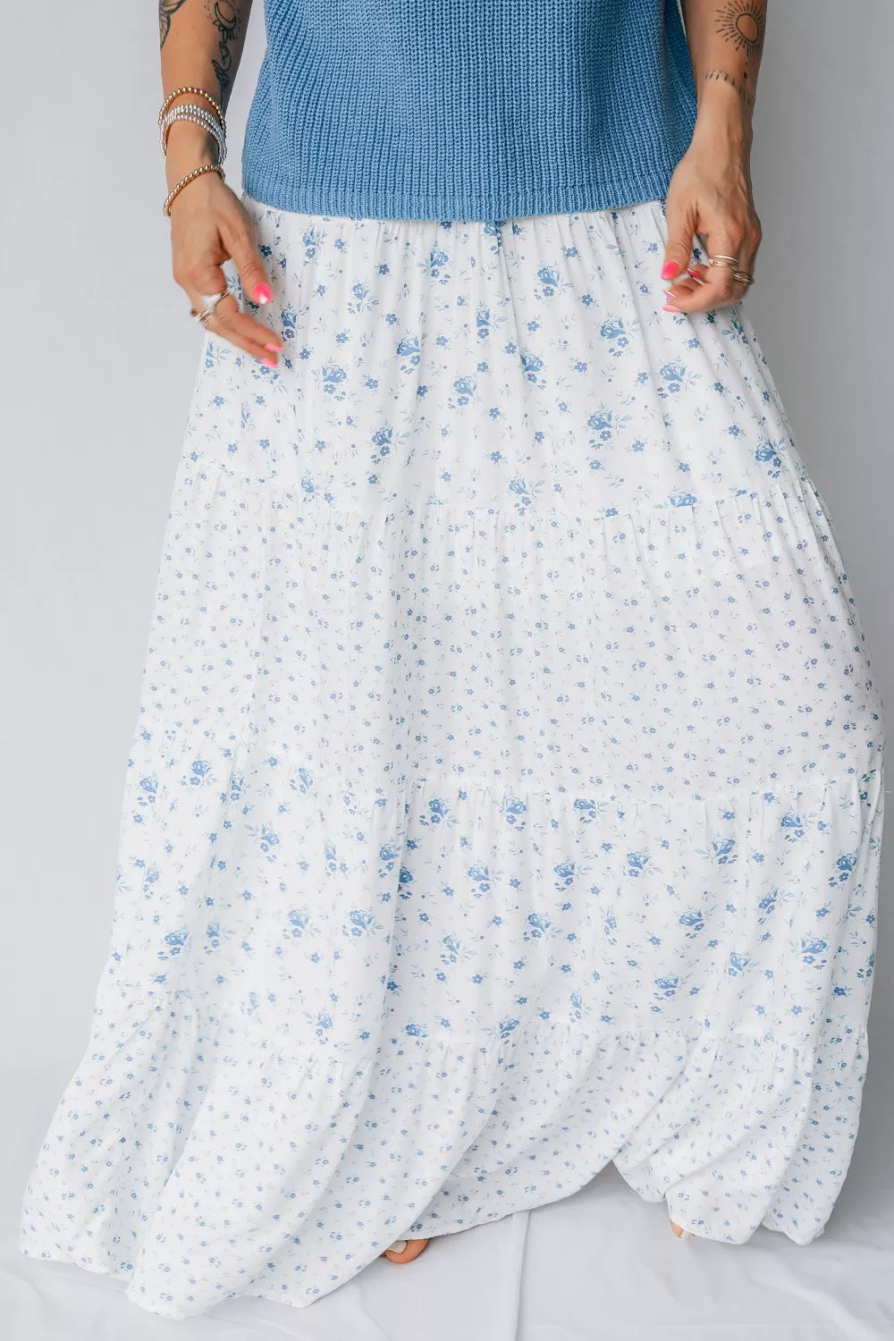 Bohemian tiered maxi skirt with a blue floral print on white fabric.