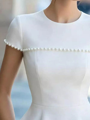 White maternity t-shirt with short sleeves and pearl embellishments on the neckline and cuffs.