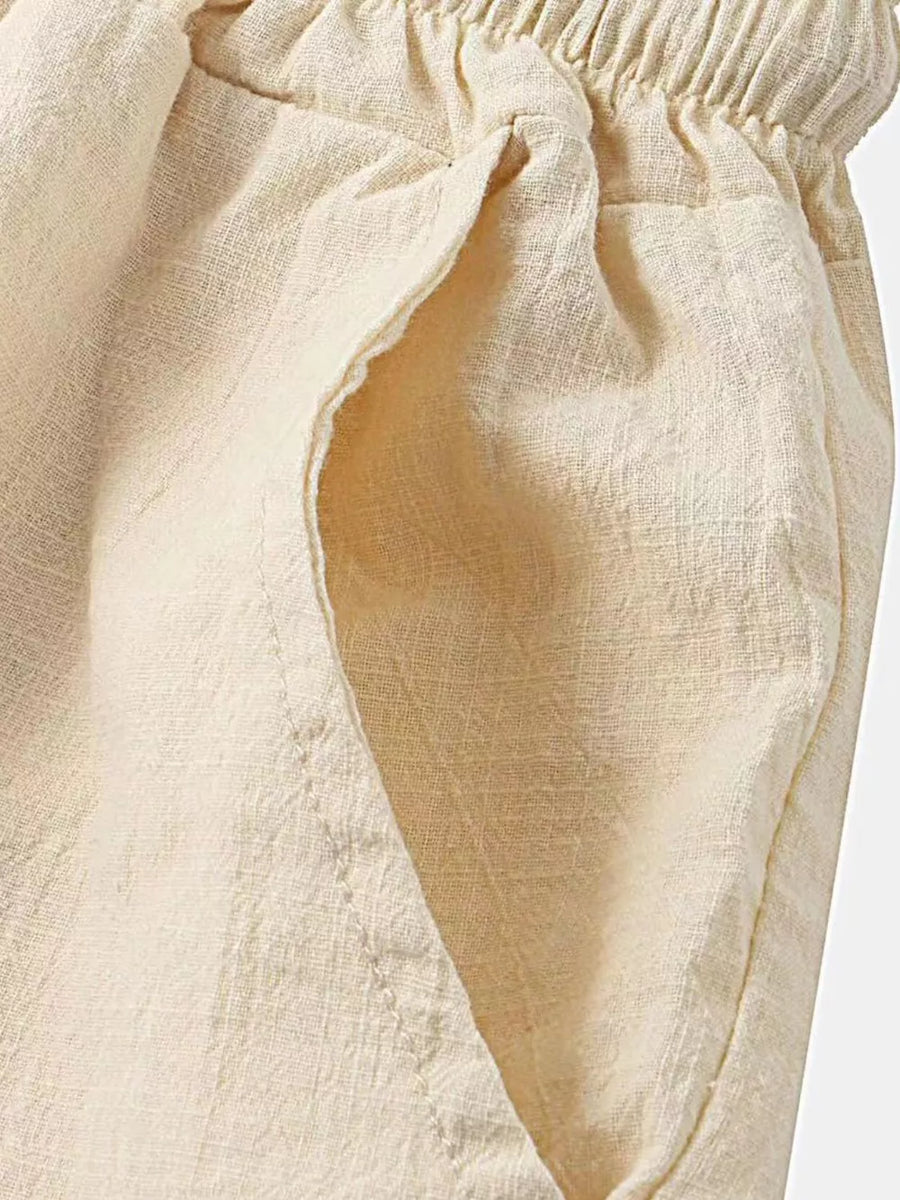 Cream linen shorts with elastic waistband and side pockets.