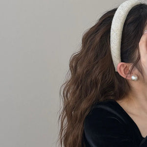 Textured tweed padded headband in a light neutral color with a subtle herringbone pattern.