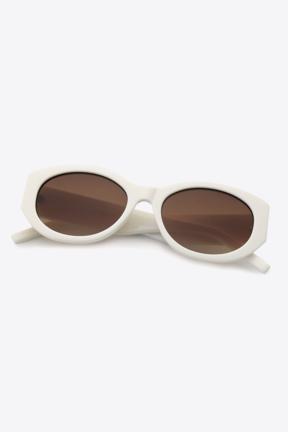 Sculpted oval frame sunglasses in beige with brown lenses and a white frame.