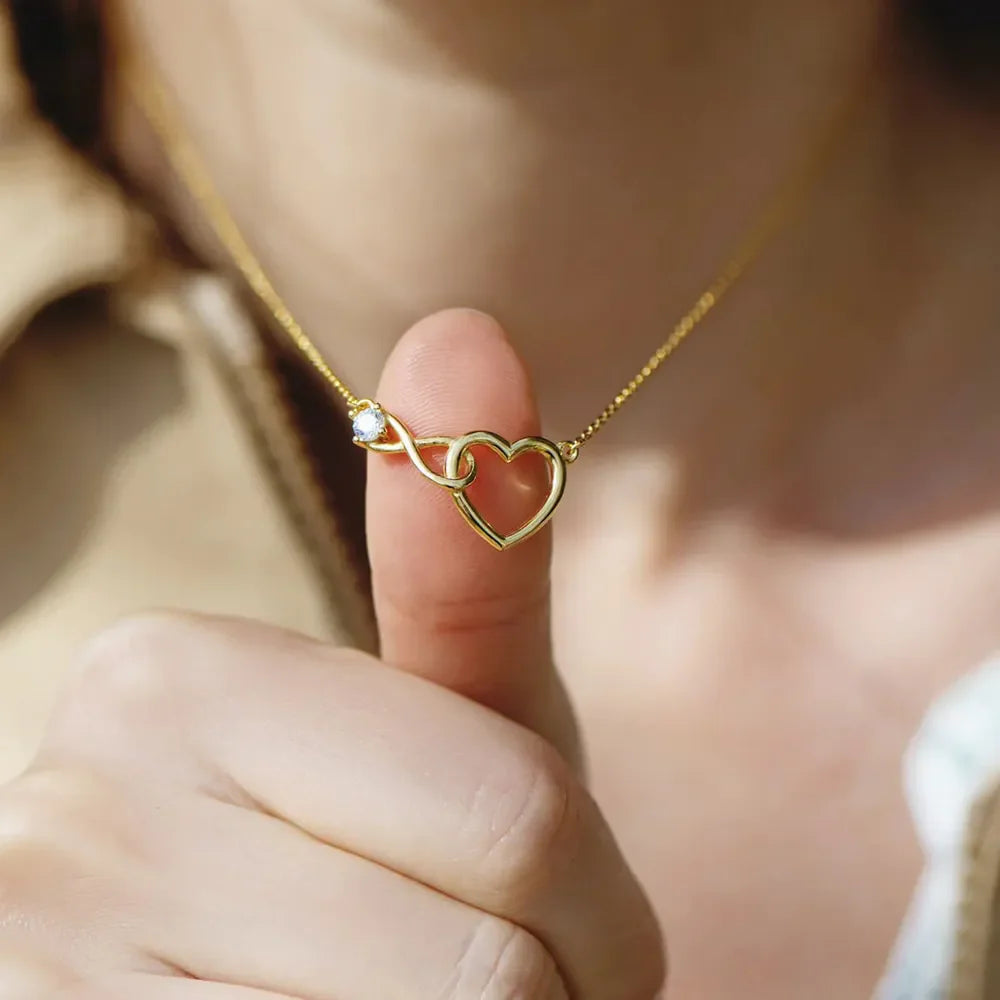 Gold necklace with intertwined heart and infinity symbol pendant and clear stone